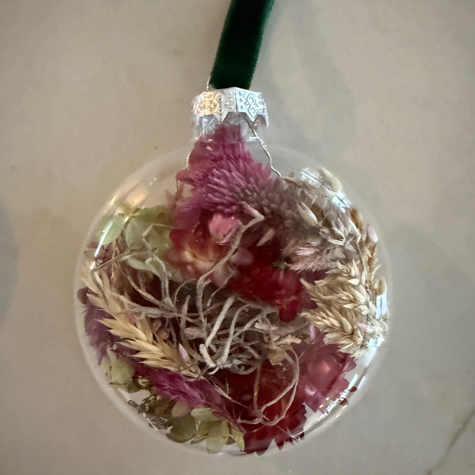 Round decorative glass ornament with dried flowers and greenery on a neutral background sweet valley flowers langley